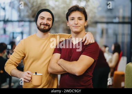 Erfolgreiche Geschäftsleute stehen selbstbewusst im modernen Büro. Männliche Person mit einer Tasse Tee oder Kaffee. Stockfoto