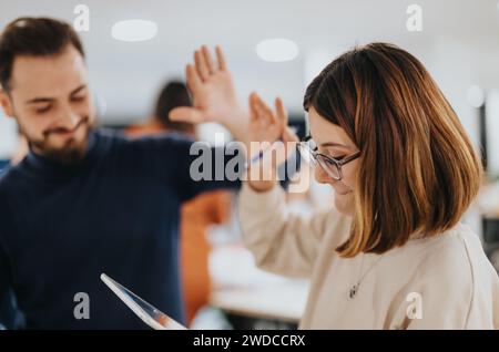 Erfolgreiche Arbeit spät in der Nacht im Büro. Zwei Mitarbeiter, die sich nach einer erfolgreichen Lösung für ein anderes Problem gegenseitig fünf geben. Stockfoto