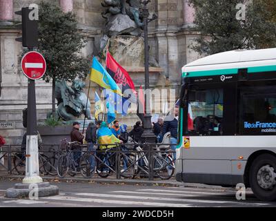 Eine Gruppe von Menschen demonstriert neben einem Bus in der Nähe einer Statue in einem urbanen Herbstszenario, Demonstration für die Ukraine .Paris Stockfoto