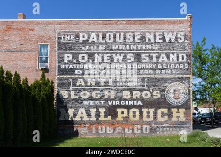 Palouse, WA, USA - 23. Mai 2023; alte Backsteinmauer mit bemalten historischen Schildern Stockfoto