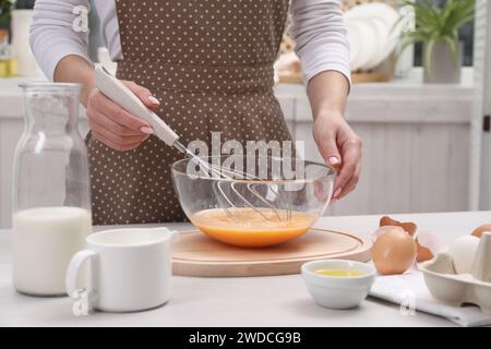 Frau, die Eier in einer Schüssel an einem Tisch drinnen rausquetscht, Nahaufnahme Stockfoto