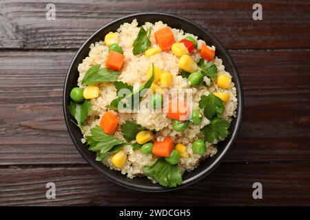 Leckerer Quinoa-Brei mit Gemüse in Schüssel auf Holztisch, Blick von oben Stockfoto