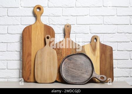 Verschiedene Schneidebretter aus Holz auf dem Lichttisch in der Nähe der weißen Ziegelwand Stockfoto