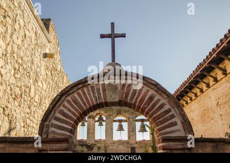Holzkreuz auf einem Bogen mit Glocken bei Mission San Juan Capistrano in Kalifornien Stockfoto