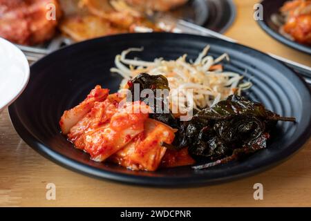Koreanische Beilagen, Kimchi, gewürzte Bohnensprossen, in Soße marinierte Sesamblätter Stockfoto