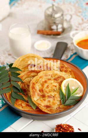 Roti Parata oder Roti Canai mit Lammcurry-Sauce, serviert mit Chilli-Flakes und Tee. Stockfoto