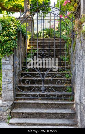 Ein geschlossenes schmiedeeisernes Tor blockiert den Zugang zu Treppen, die zu einer Privatresidenz in Varenna, Lombardei, Italien führen. Stockfoto