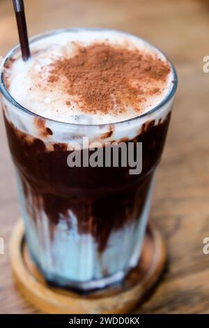 Eischokolade mit Schlagsahne und Kakaopulver auf Holztisch. Stockfoto