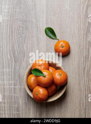 mandarinen-Mandarinengruppe in Holzschale reif und frisch mit Blatt auf hölzernem Hintergrund Stockfoto