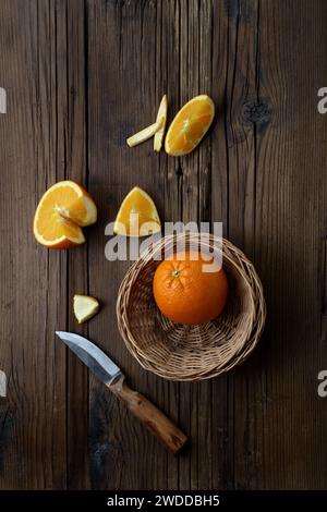 Orange mit Scheiben und Khife auf Holztisch, Obst-Thema Stockfoto
