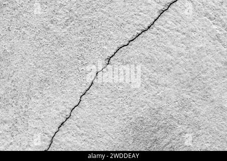 Großer Riss an der alten Putzwand. Lange Wicklungen, aufsteigender Riss in der Zementoberfläche eines alten Gebäudes. Speicherplatz kopieren. Selektiver Fokus. Stockfoto