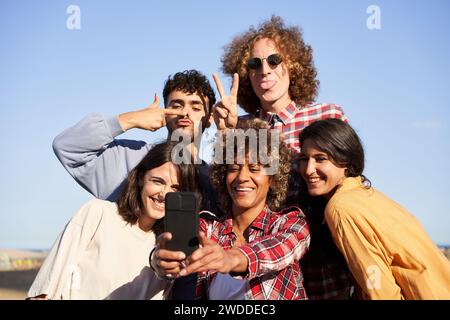 Junge Erwachsene Gruppe verschiedene fröhliche Freunde, die lustiges Selfie-Telefon machen. Millennials multirassische Menschen. Stockfoto