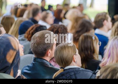 Eine Menge aufmerksamer Menschen mit unterschiedlichem Hintergrund versammelte sich bei einer Veranstaltung oder einem Seminar im Freien. Stockfoto