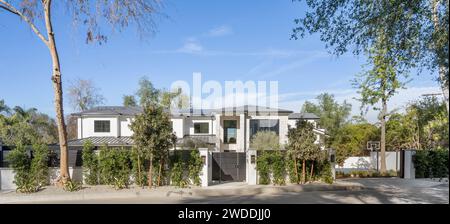 Ein bezauberndes weißes Haus liegt eingebettet zwischen üppigem Laub von Bäumen und Büschen an einer ruhigen Straße, New Construction Home in Tarzana, Kalifornien Stockfoto