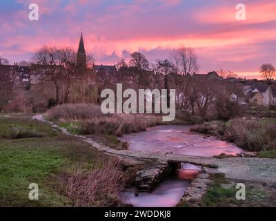 Samstag, 20. Januar 2024. Malmesbury, Wiltshire, England - wenn die Sonne über der gefrorenen Wasserwiese und der alten Clapper Bridge aufgeht, färbt sich der Himmel über der malerischen Marktstadt Malmesbury in Wiltshire rot. Quelle: Terry Mathews/Alamy Live News Stockfoto