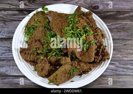 Traditionelle arabische frittierte Rindleberscheiben, Rindleber bedeckt mit Weizenkleie (Kebda Bel Rada), was bedeutet, gebratene Leileber, serviert mit Parsel Stockfoto