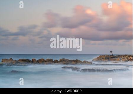 Meereswasser, das bei Sonnenaufgang über Felsen und Riff an der Küste von Curacao in der Karibik kaskadiert. Stockfoto