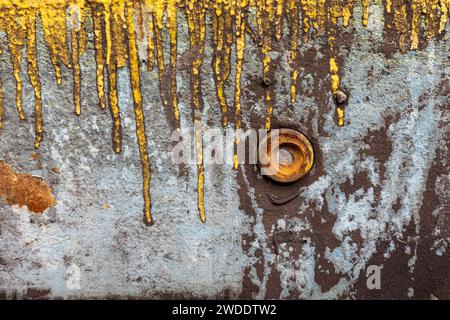 Eine verrostete Schraubenmutter auf einer verwitterten Metallplatte mit gelben Lackrissen Stockfoto