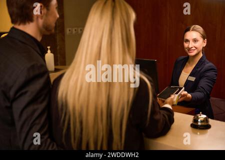 Pärchen, die kontaktlos telefonieren über Terminal an der Rezeption bezahlen Stockfoto