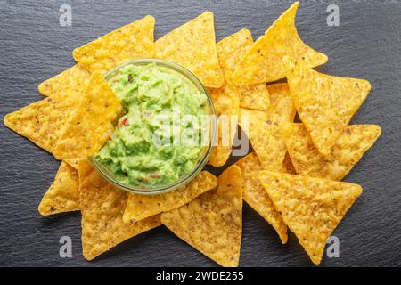 Guacamole-Sauce und Tortilla-Chips, beliebtes mexikanisches Essen, auf Schiefertafel. Draufsicht. Stockfoto