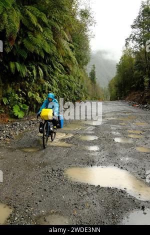 Radfahrer, die auf einer Schotterpiste im Pumalin-Nationalpark an der Carretera Austral in Chile durch den Regen fahren Stockfoto