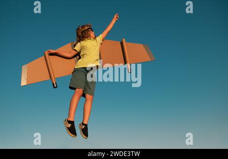 Kids Leader und Gewinner, Erfolg beginnt. Junge Pilot fliegen gegen einen blauen Himmel. Aufgeregt Kind Junge spielen mit Spielzeug Jetpack Flügel Superheld im Park. Stockfoto