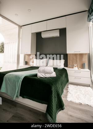 Inneneinrichtung des stilvollen grünen Schlafzimmers mit weißer Holzwand. Stockfoto