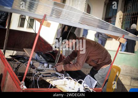 Rafah, Palästinensische Gebiete. Januar 2024. Ein Palästinenser lädt Telefone an einer Ladestation auf, die von einem Solarpanel in einem Flüchtlingslager in Rafah gespeist wird. Aufgrund der sich verschlechternden finanziellen Lage der Einzelpersonen und des Strommangels in den Flüchtlingslagern in Rafah, einige junge palästinensische Männer, die über Solarzellen verfügen, nutzen sie, um kleine Unternehmen zu betreiben, mit denen sie den Menschen erlauben, ihre Telefone für etwa 2 israelische Schekelgebühren (etwa 55 US-Cent) vollständig aufzuladen. Quelle: Mohammed Talatene/dpa/Alamy Live News Stockfoto