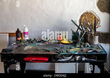 Unordentlicher Künstlertisch mit Pinseln und anderen Kunstgegenständen im Kunststudio Stockfoto