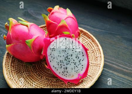 Frisch reife Drachenfrucht in zwei Hälften mit ganzen Früchten in einem Korb Stockfoto