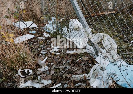 Plastikmüll in einem Drahtzaun gefangen. Entfernen von Müll aus der Natur. Stockfoto