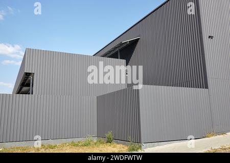 Gewelltes Stahllager oder Fabrikgebäude vor blauem Himmel. Architektur. Metallstruktur Stockfoto