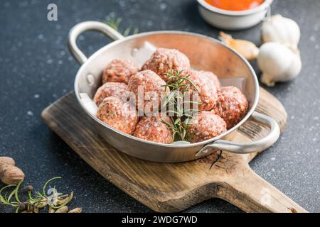 Rohe Fleischbällchen in der Pfanne auf dem hölzernen Schneidebrett Stockfoto
