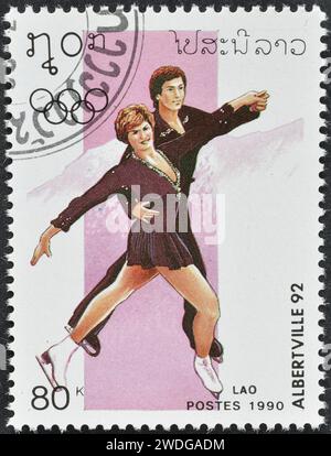 Gestempelte Briefmarke, gedruckt von Laos, die Eiskunstlauf zeigt, Werbung für die Olympischen Winterspiele 1992 - Albertville, um 1990. Stockfoto