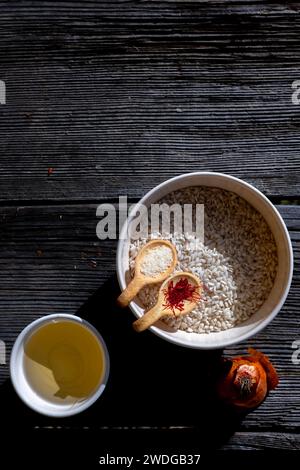 Rohe Zutat zur Herstellung des Safranreises, Risotto alla Milanese mit Parmesan und Weißwein und Zwiebeln auf einem alten Holztisch mit Sonnenlicht Stockfoto