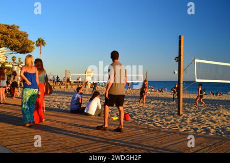 Die Leute spazieren gerne auf der Promenade in Laguna Beach, Kalifornien, und beobachten, wie sich Meer und Küste treffen und Freunde Beachvolleyball spielen Stockfoto