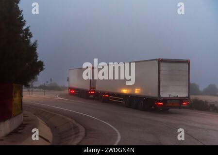 Duo-Anhänger-Lkw fährt an einem nebeligen Tag auf einer Nebenstraße. Stockfoto