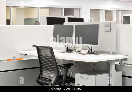 Leerer Büroschreibtisch mit Computermonitoren, Schreibtisch und Stuhl in einer Kabine. Konzeptbild „Arbeiten von zu Hause aus“. Stockfoto