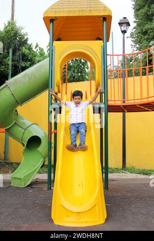 Der 9-jährige dunkelhäutige Latino-Junge spielt auf einem Spielplatz als körperliche Aktivität und lebt in Armut als Therapie für ADHS Stockfoto