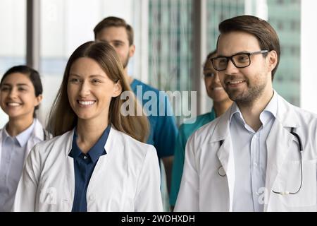 Fröhliche junge Praktizierende, die zusammen zum Schießen stehen und wegschauen Stockfoto