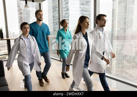 Verschiedene junge Ärzte in Uniformen, die an der Kamera vorbeilaufen Stockfoto