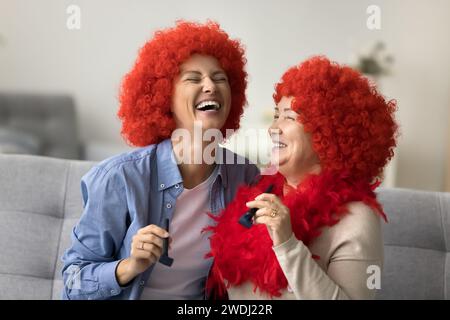 Aufgeregte Mutter und Erwachsene Tochter tragen Clown Perücken und haben Spaß Stockfoto