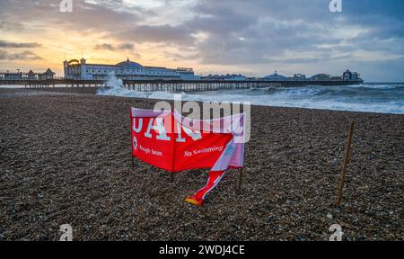 Brighton UK 21. Januar 2024 - Ein Gefahrenschild am Strand von Brighton wird heute Morgen von starken Winden zerrissen, da der Sturm Isha später heute über Großbritannien fegen wird, wobei bernsteinfarbene Wetterwarnungen ausgegeben werden, die Windprognosen in einigen Teilen 8 km/h erreichen: Credit Simon Dack / Alamy Live News Stockfoto