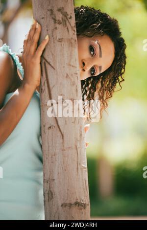 Frau versteckt sich hinter Baum Stockfoto