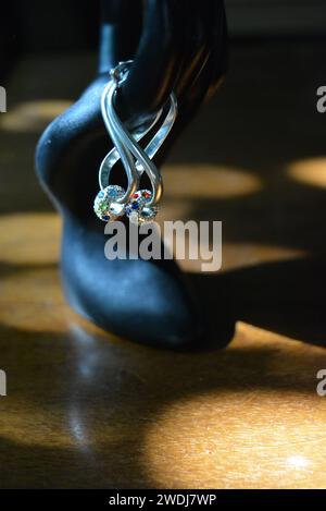 Schwarze Statuette einer matten weiblichen Hand mit silbernen Ohrringen mit schönen Steinen und einem Anhänger. Stockfoto