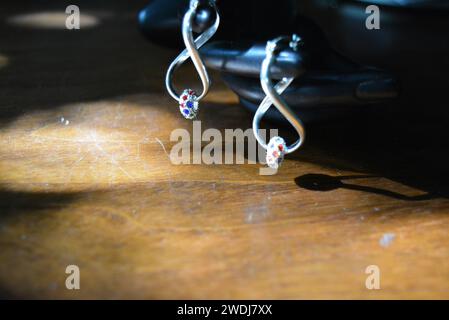 Schwarze Statuette einer matten weiblichen Hand mit silbernen Ohrringen mit schönen Steinen und einem Anhänger. Stockfoto