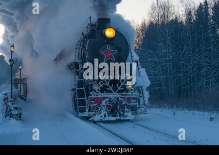 KHELYULYA, RUSSLAND - 20. JANUAR 2024: Alte Dampflokomotive der L-Serie mit dem Ruskealsky Express-Zug kommt am Bahnhof Moroznaya in Janua an Stockfoto