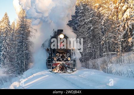 RUSKEALA, RUSSLAND - 20. JANUAR 2024: Alte Dampflokomotive der L-Serie des Ruskeala Express-Zuges in einem Winterwald an einem Januarmorgen Stockfoto