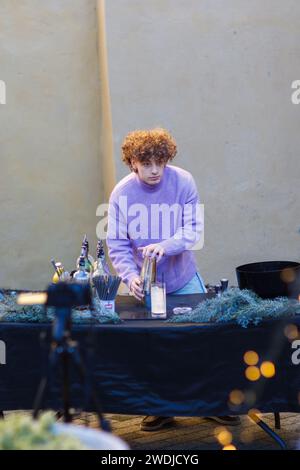 kaukasischer junger, kühl rothaariger Barista, der im Winter bei einem privaten Event im Shaker einen Cocktail mit Energie im Freien mischt Stockfoto