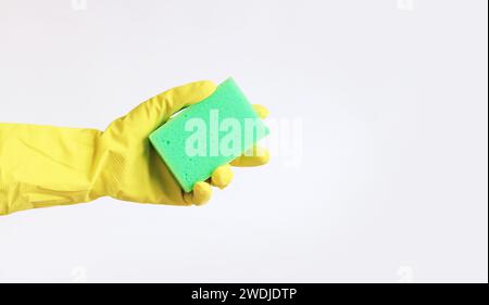 Die Hand einer Frau in einem gelben Latexhandschuh hält einen Spülschwamm. Reinigung der Räumlichkeiten. Professionelle Reinigung. Haushaltshandschuhe, gelb. Reinigungsauftrag Stockfoto